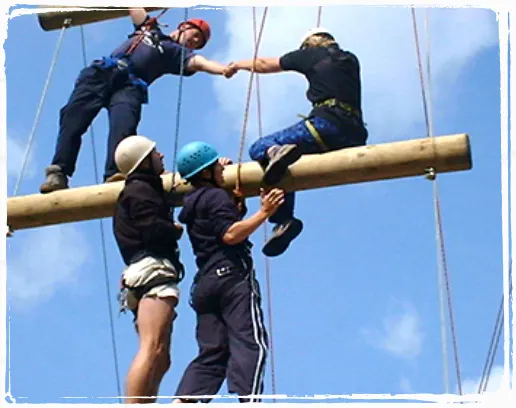 person on a high wooden beam assisted by professionals 