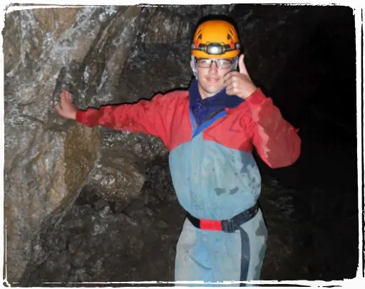 A young adult giving a thumbs up in a cave